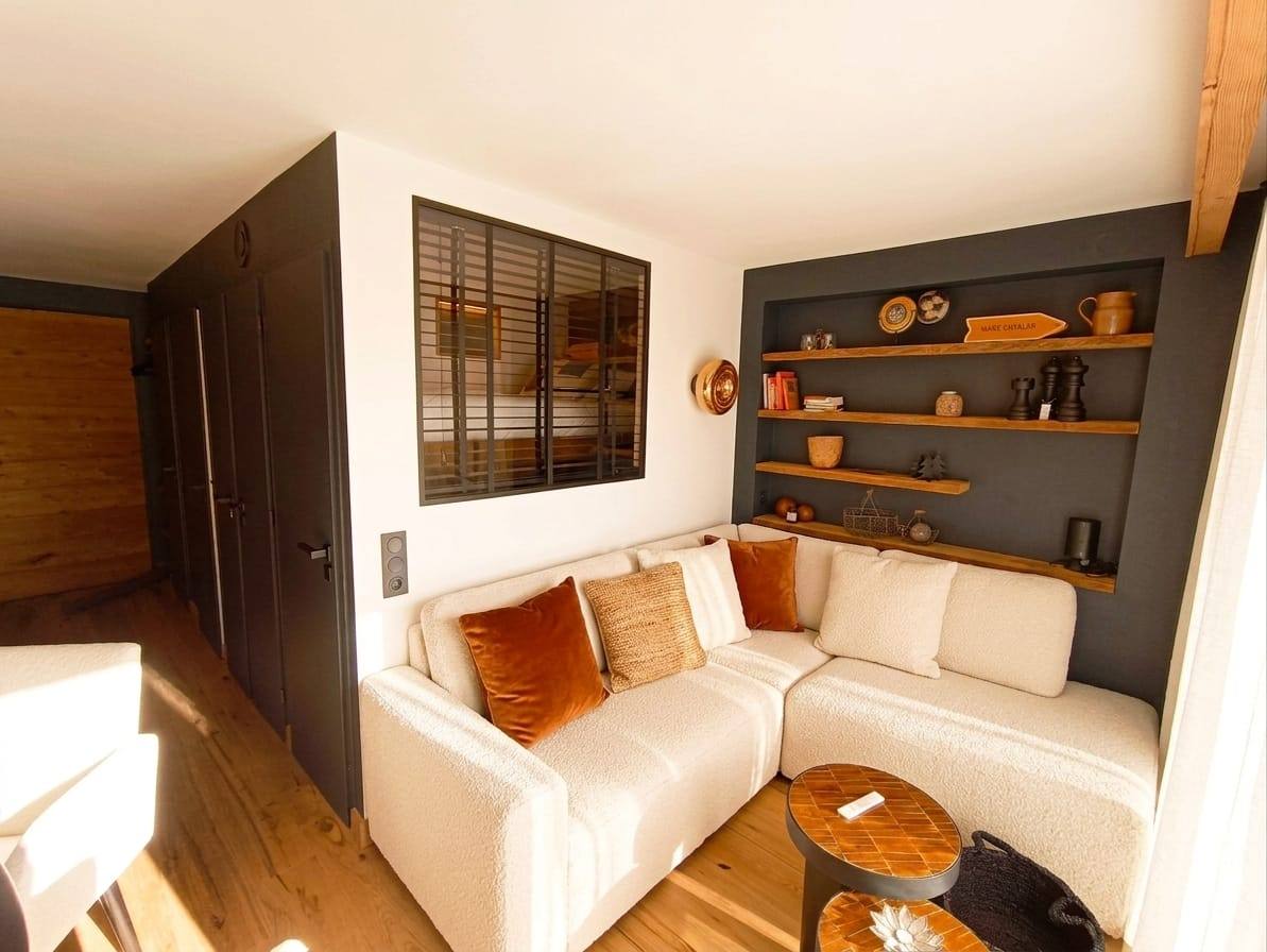 Salon de chalet entièrement rénové dans le Briançonnais : parquet en bois, poutres apparentes et finitions soignées par Concept Rénovation