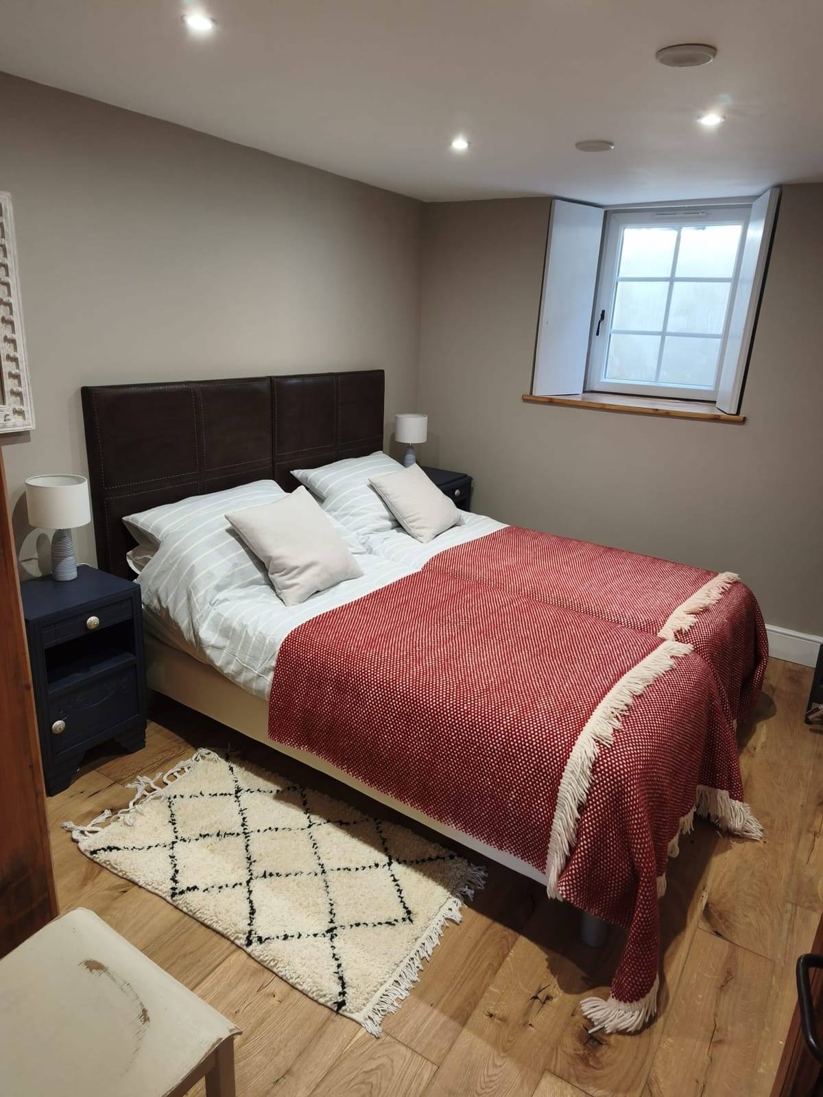Chambre rénovée sous combles avec parquet en chêne, murs beiges, spots encastrés et fenêtre de toit