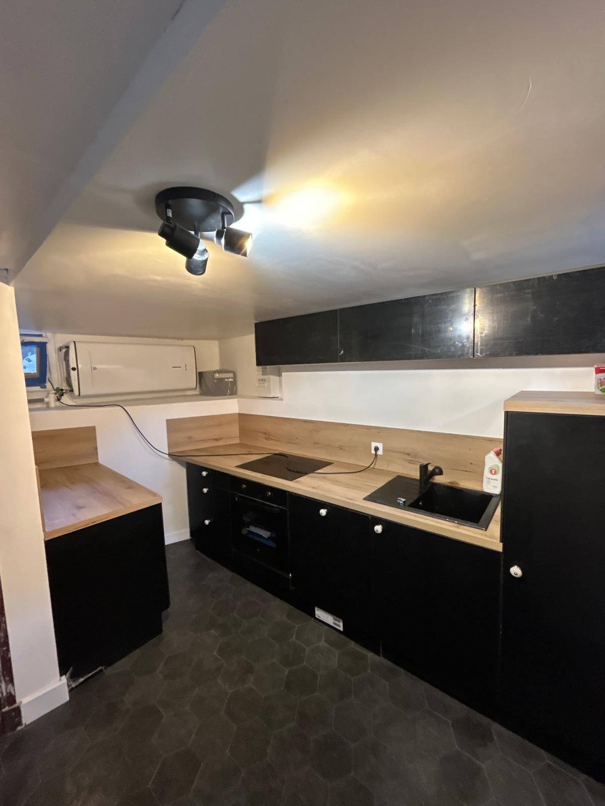 Cuisine rénovée avec façades noires, plan de travail bois et plaque induction dans le Briançonnais