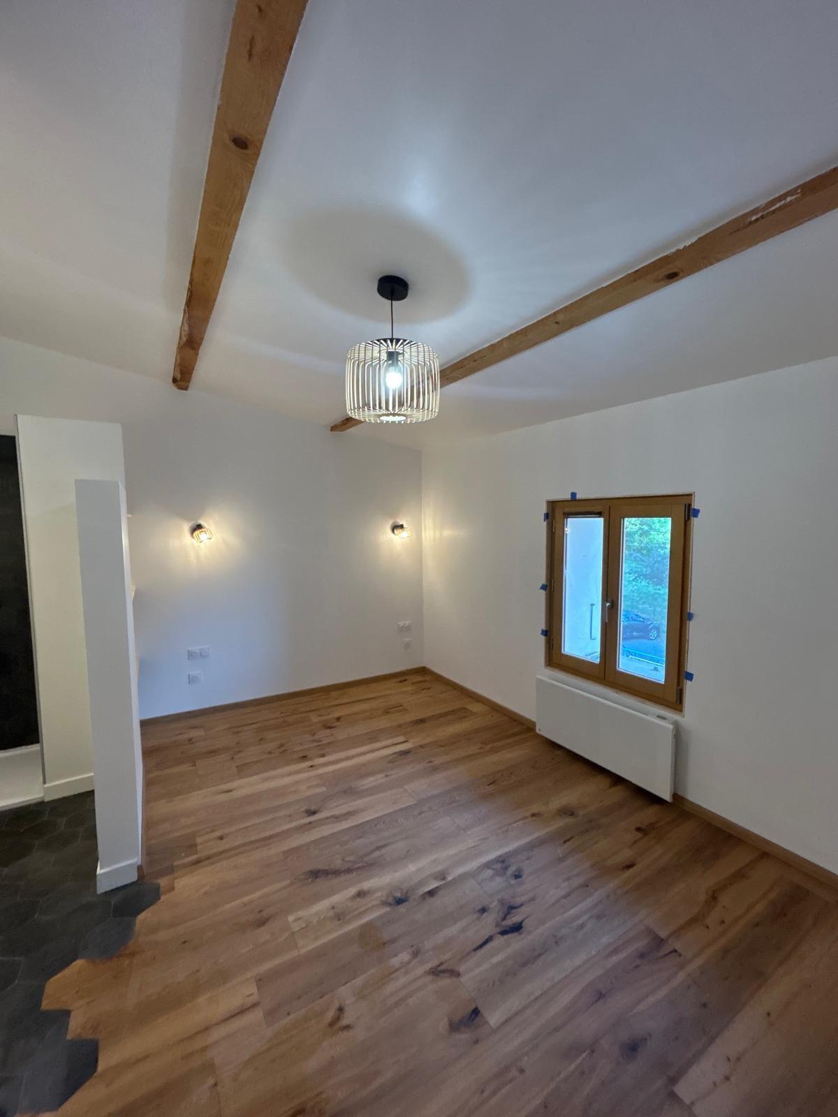 Pièce de vie rénovée avec parquet en chêne massif et poutres apparentes, signature d’une rénovation soignée dans le Briançonnais